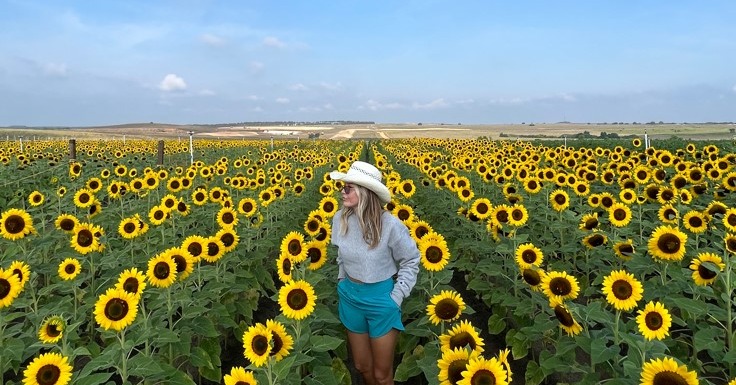 Woman standing in sunflower rows