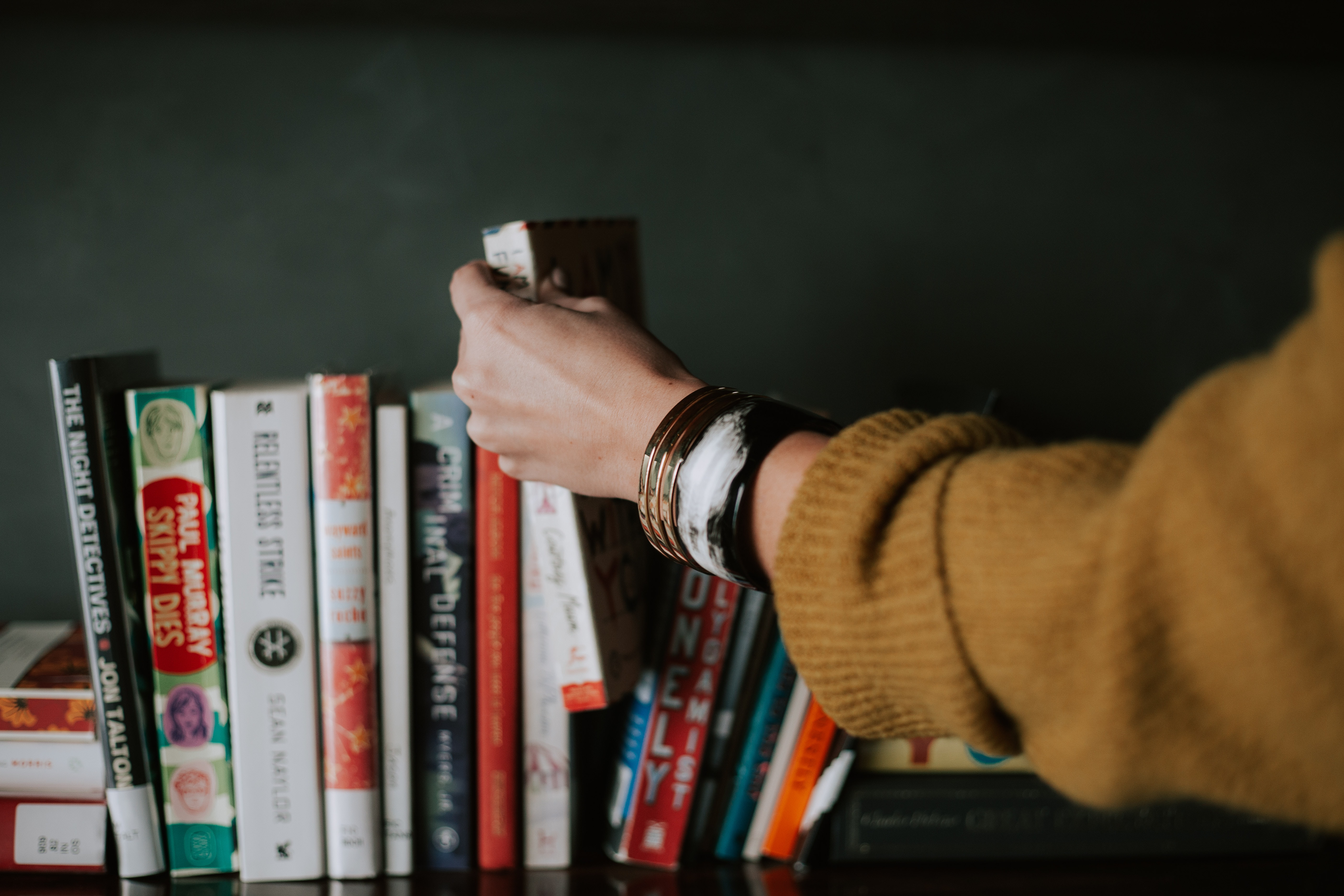 woman taking book of shelf